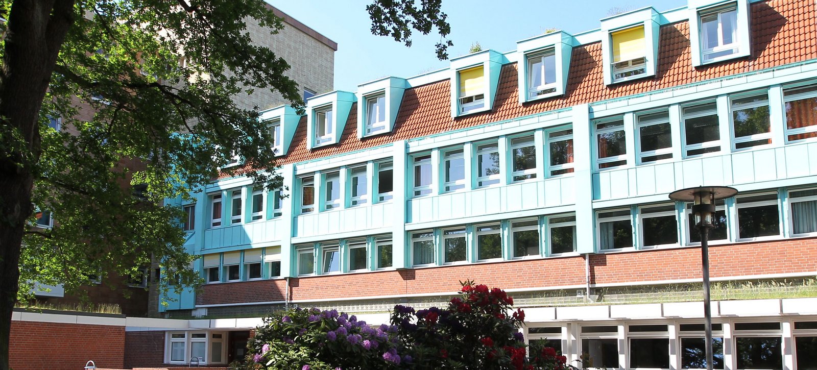 Blick auf die Evangelische Hochschule durch den blühenden Park.