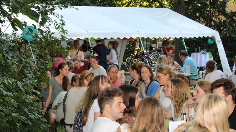 Studierende sitzen gemeinsam draußen um das Welcome Back Sommerfest 2022 zu feiern
