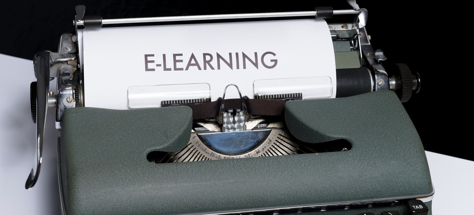 In einer alten, analogen Schreibmaschine steckt ein Blatt Papier, auf dem E-Learning steht