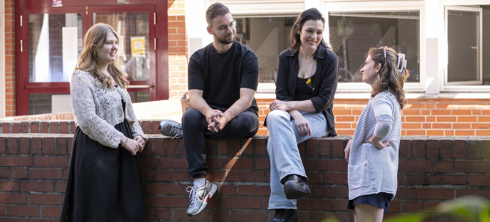 Studierende stehen vor der Evangelischen Hochschule und unterhalten sich fröhlich.